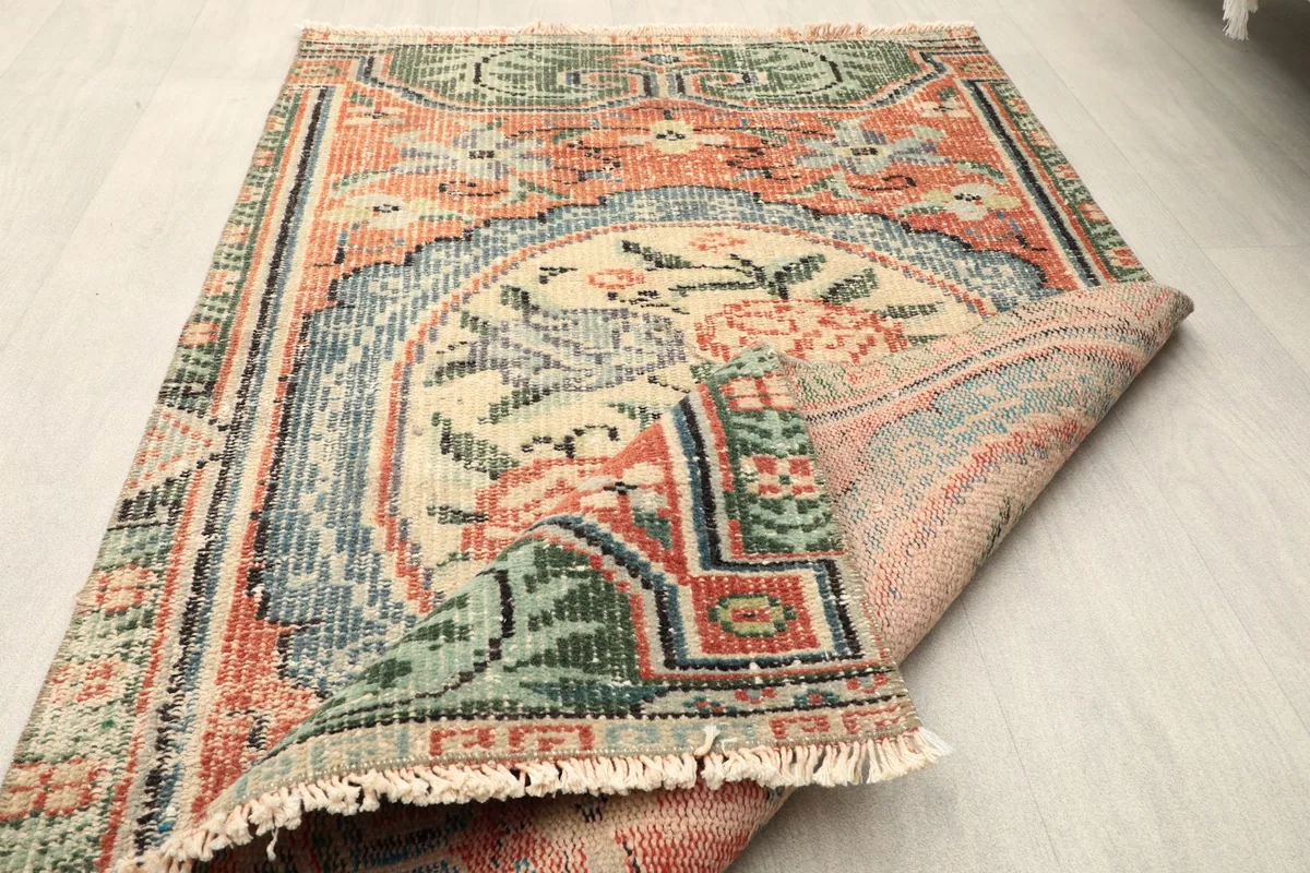 The vintage rug partially folded, showcasing both the front design and the back of the rug