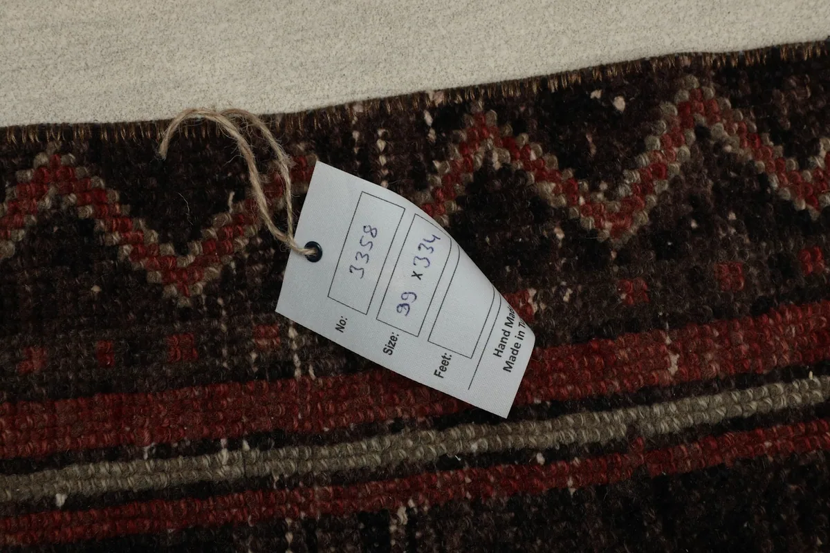 Close-up of the rug's tag displaying size 99 x 334 cm and hand-made details