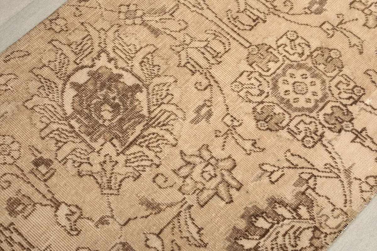 Detailed view of a central floral motif with surrounding paisley-like designs in brown on beige.