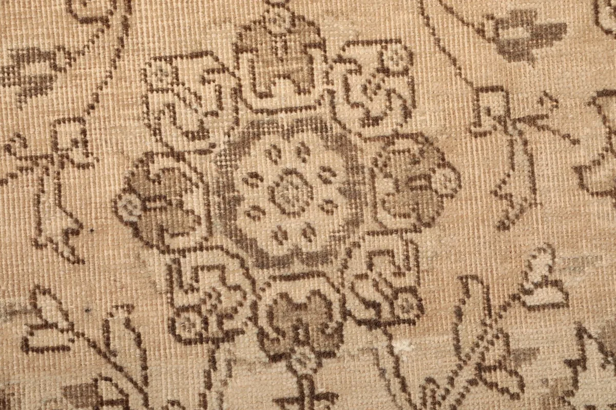 Extreme close-up of a geometric floral medallion, revealing the hand-knotted wool texture and color variations.