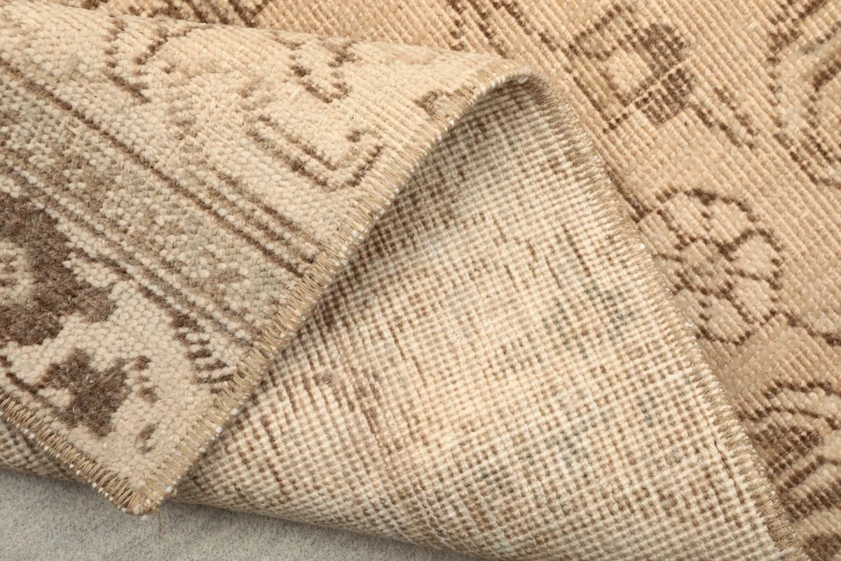 Another view of the folded rug corner, displaying the reverse side and the tight weave of the cotton foundation.