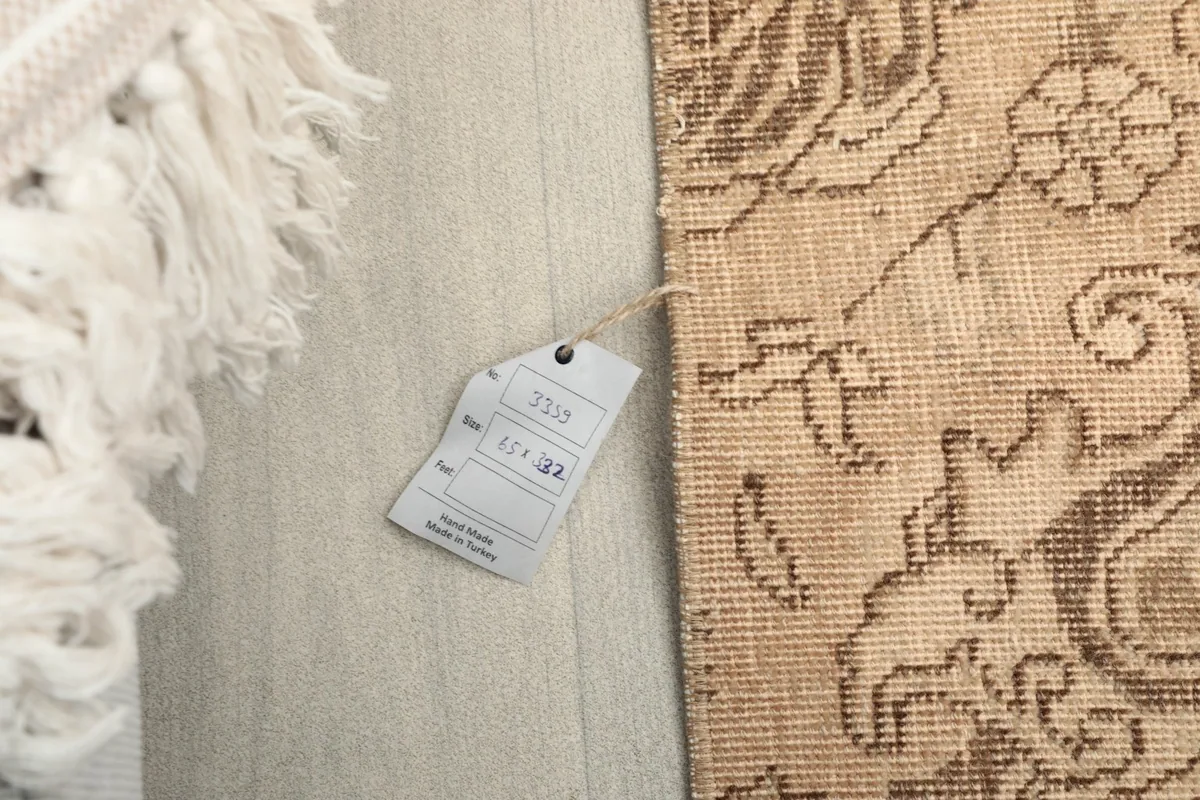 Close-up of the rug's edge with a size tag displaying '2'2" x 10'11"' and '65 x 332 cm'.