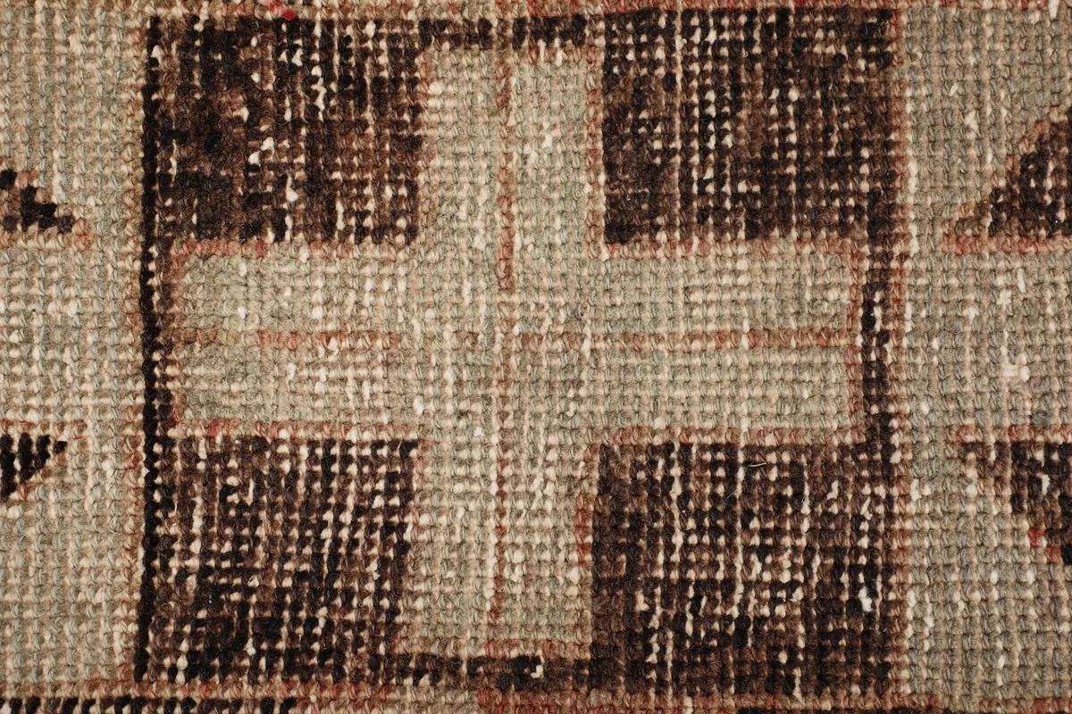 Detailed view of the low wool pile, showing the individual knots and the texture of the charcoal and beige yarns.