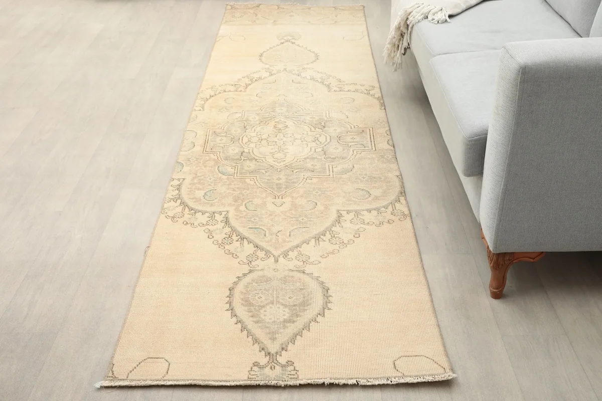 Runner rug placed in a living room next to a light gray sofa, showing its length and scale