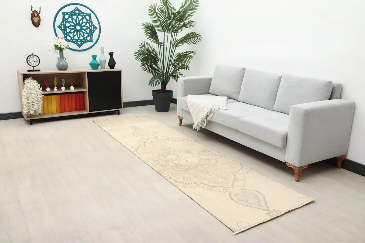 Wide shot of the rug in a living space with a sofa and side table, highlighting its muted colors