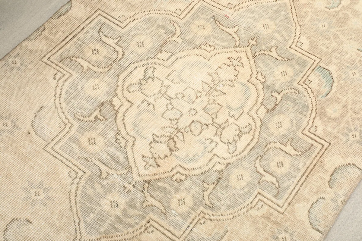 Detailed overhead view of the central medallion motif in muted gray and ivory tones