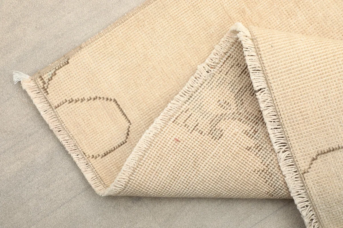 Corner of the rug folded back to show the cotton foundation and reverse side of the hand-knotted construction
