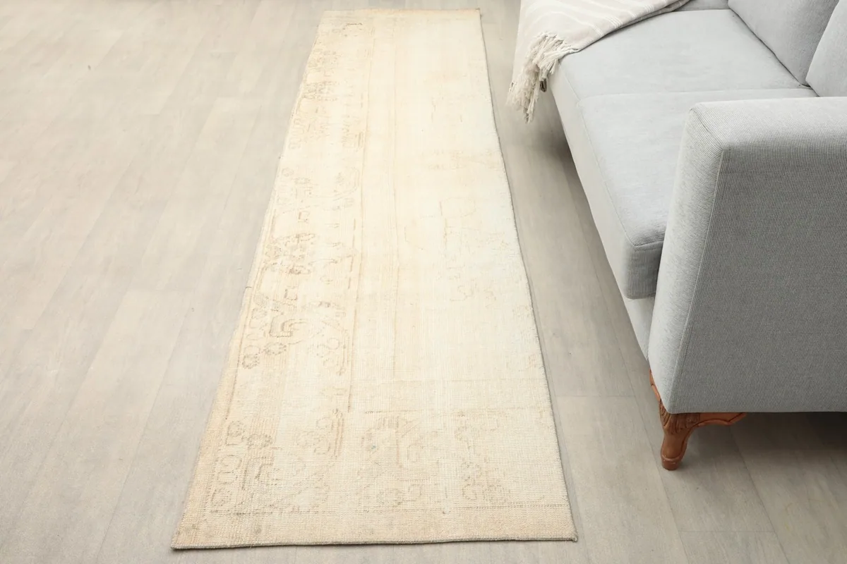 Beige runner rug on a light floor next to a gray sofa, showing its length and neutral tones
