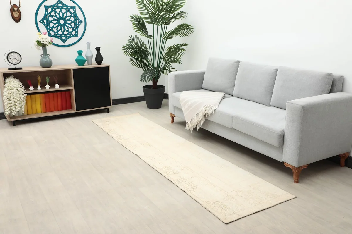 Full room view with the beige runner rug, a gray sofa, and a side table with decor