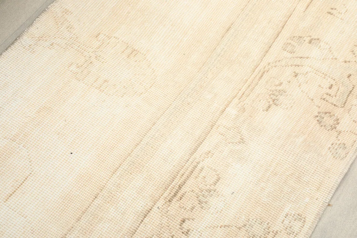 Close-up of the low wool pile texture and the muted, faded design elements