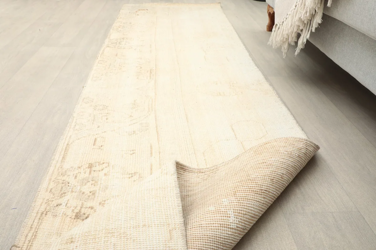 The beige runner rug partially folded, showing the pile and the cotton foundation