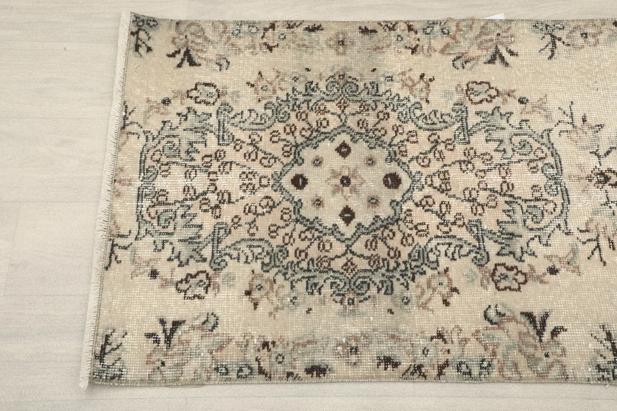 Detail view of the upper end of the rug, showing the faded central medallion and surrounding motifs