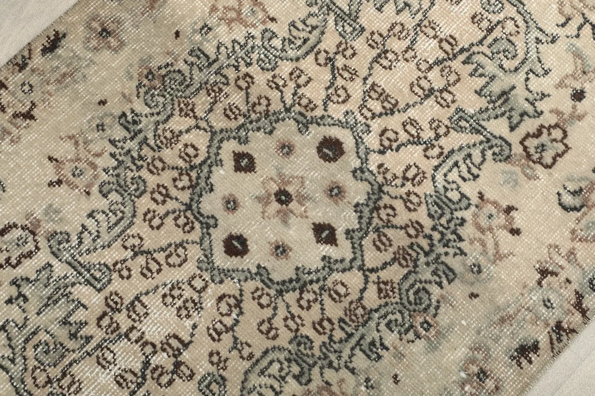 Close-up of the central medallion design with brown and gray accents on an ivory background