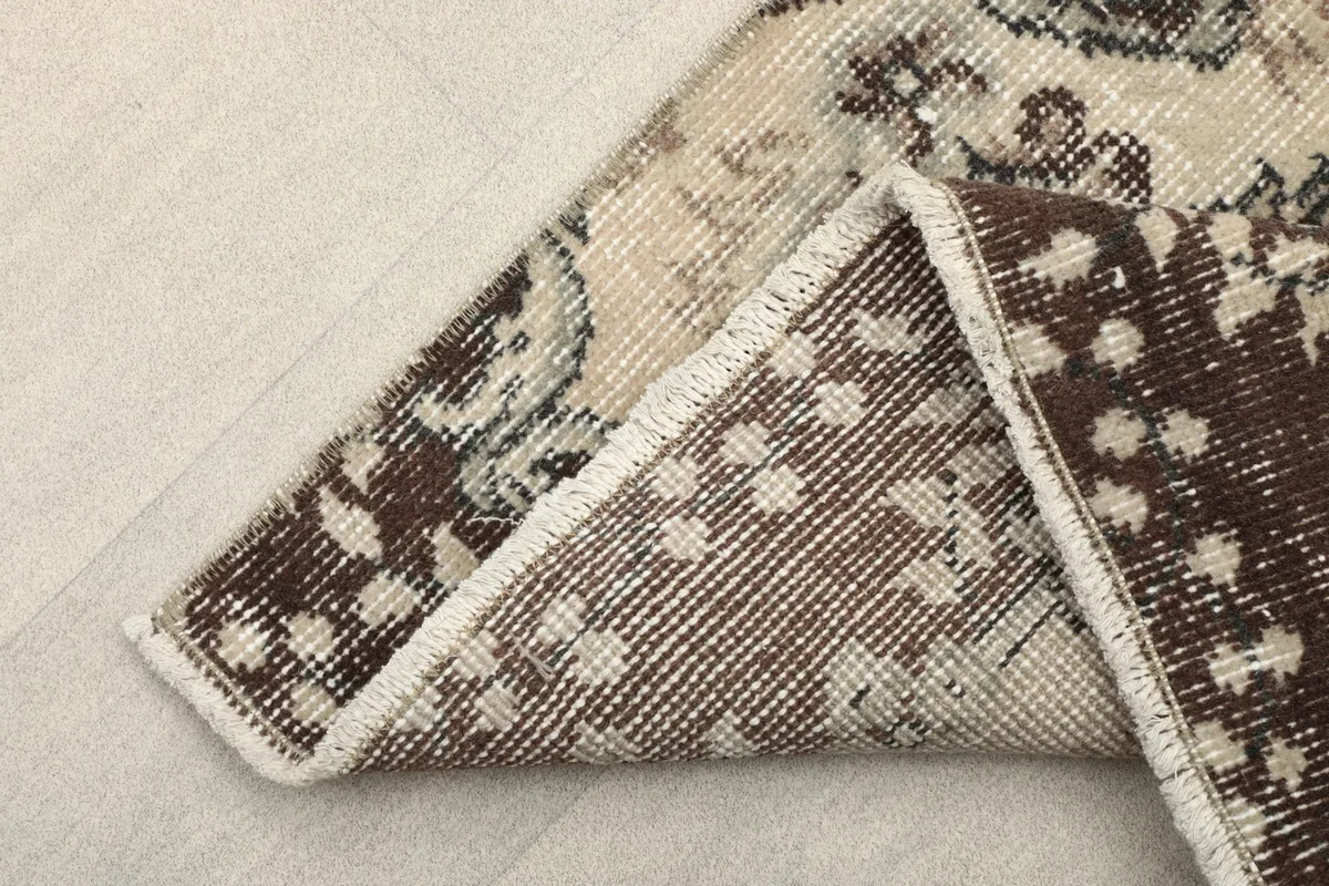 View of the back of the rug folded, showing the hand-knotted cotton foundation and wool pile