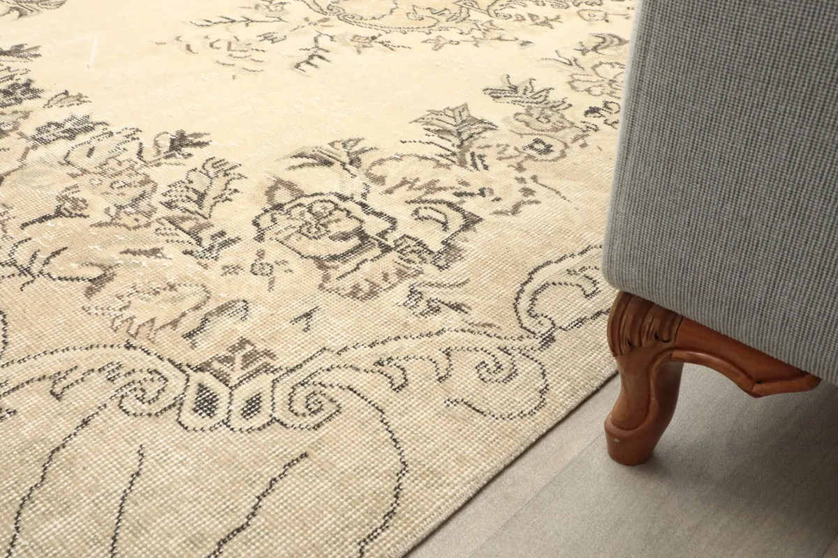 Low angle view of the rug next to a sofa leg, emphasizing the border design and room context.