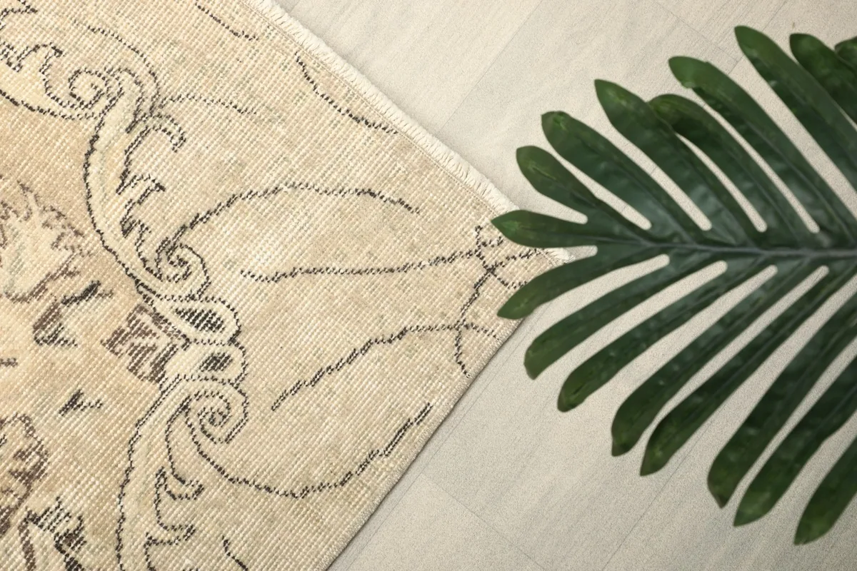 Corner detail of the rug's border and field, with a green leaf for scale and texture.