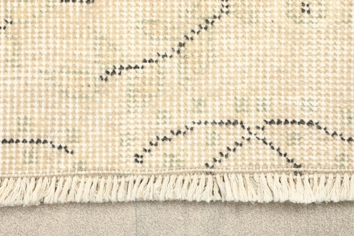 Close-up detail of the short, hand-finished fringe and the tightly woven foundation of the rug.