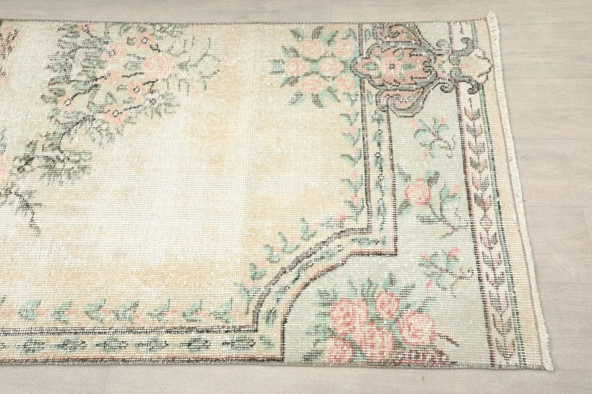 Close-up of the rug's corner showing pink floral motifs and green border details