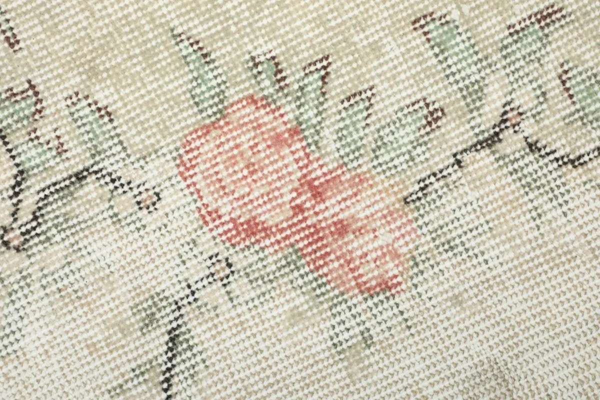 Macro shot of the rug's low wool pile and hand-knotted texture with faded colors