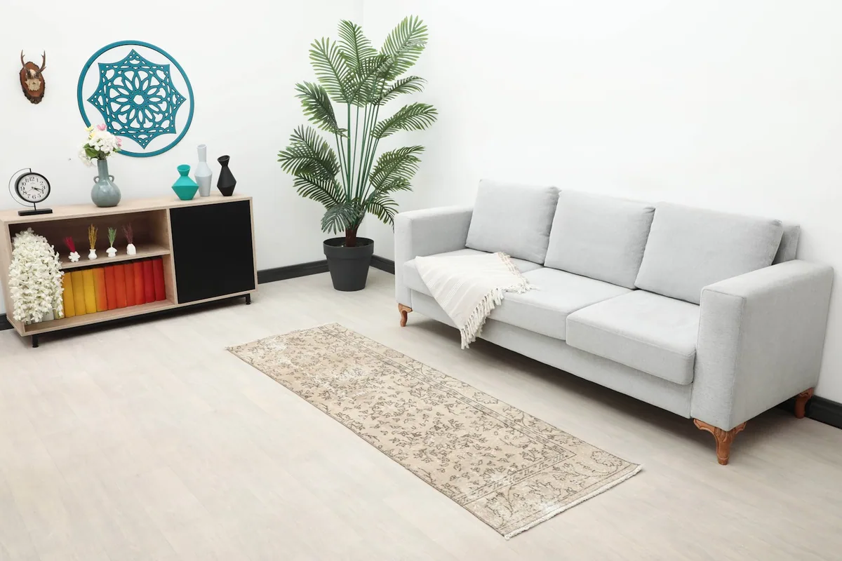 Tan floral runner rug placed in a living area with a gray sofa and modern decor