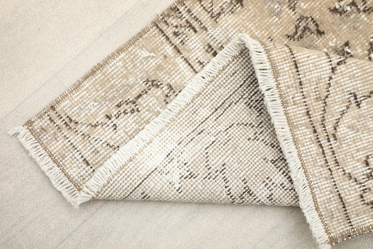 View of the back of the rug folded, showing the cotton foundation and fringe