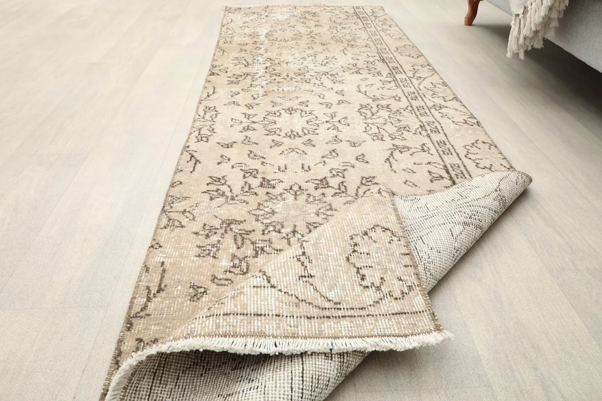 The tan runner rug partially folded, illustrating its flexibility and construction
