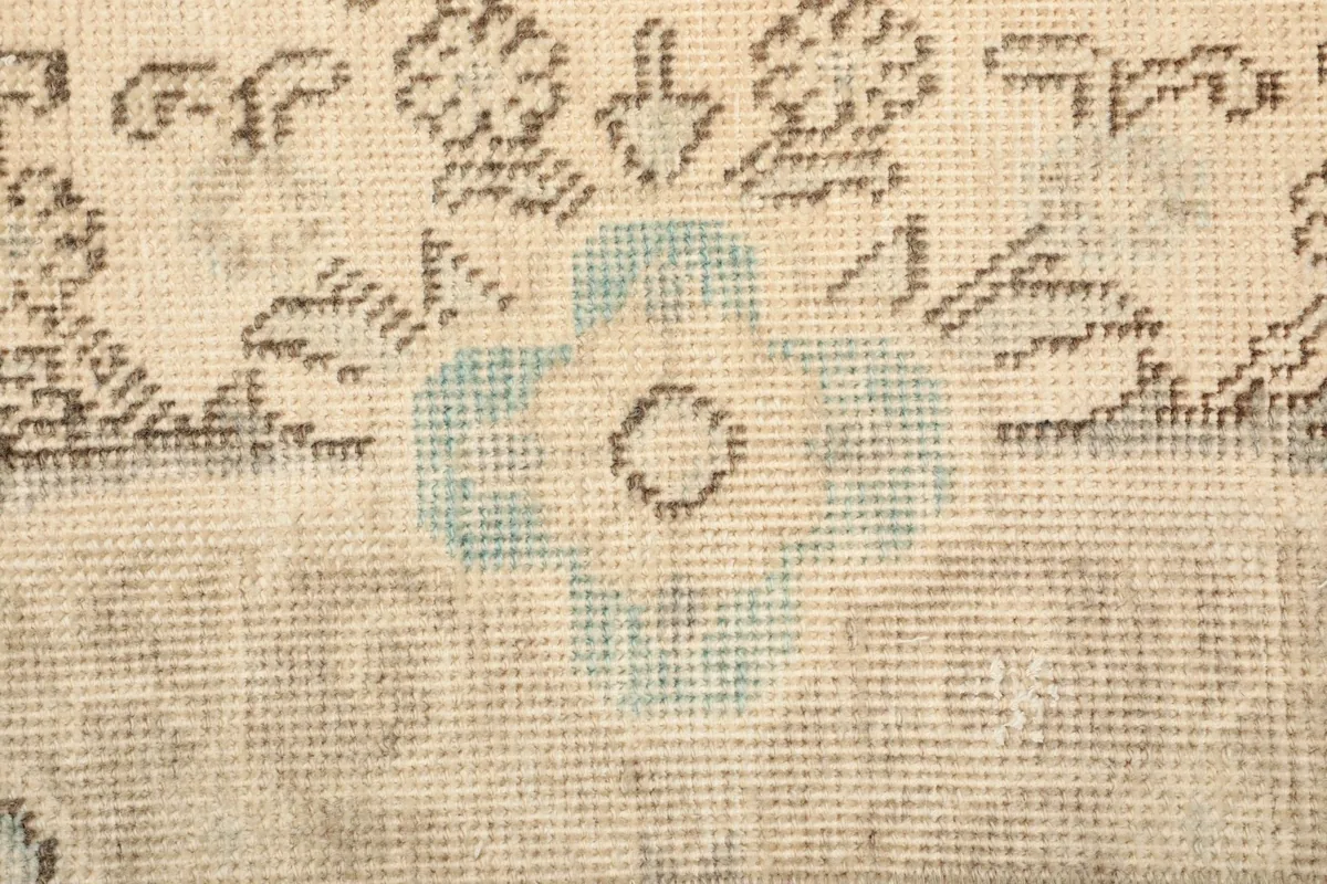 Extreme close-up of the rug's low wool pile and the intricate knotting in blue and gray tones.