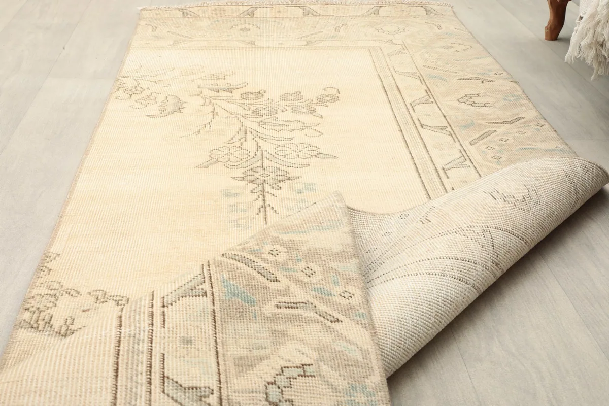The rug partially folded, showing the flexibility and thickness of the vintage wool material.