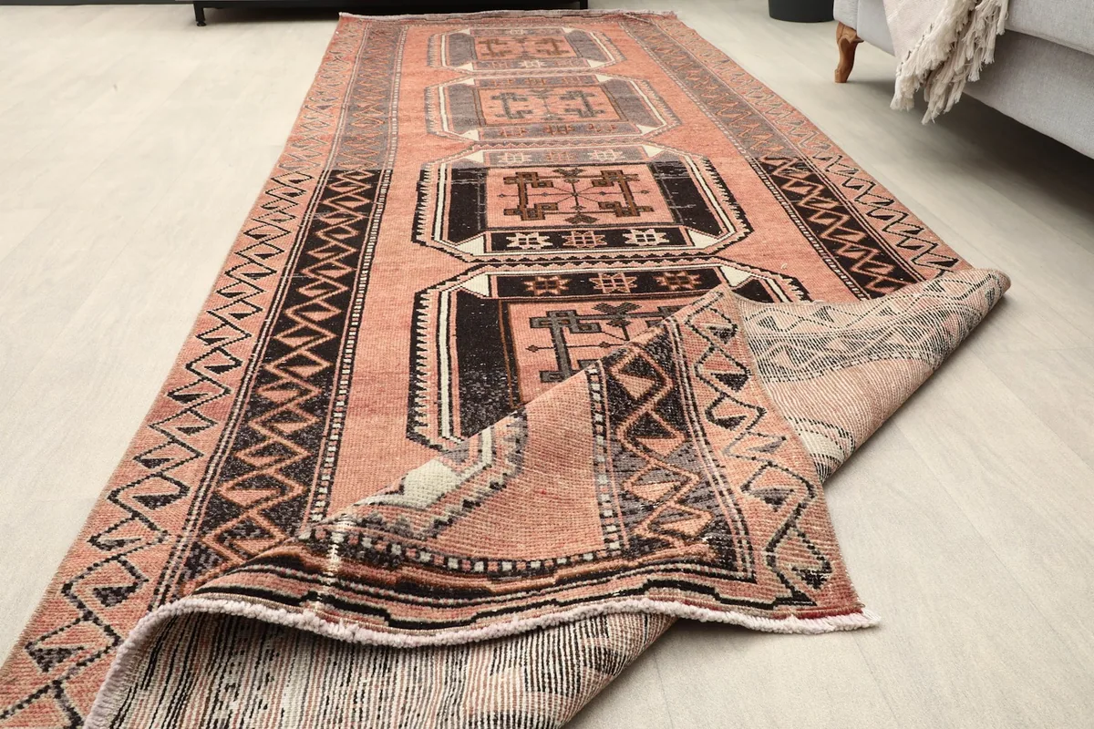Runner rug partially unrolled, showcasing its length and the reverse side.