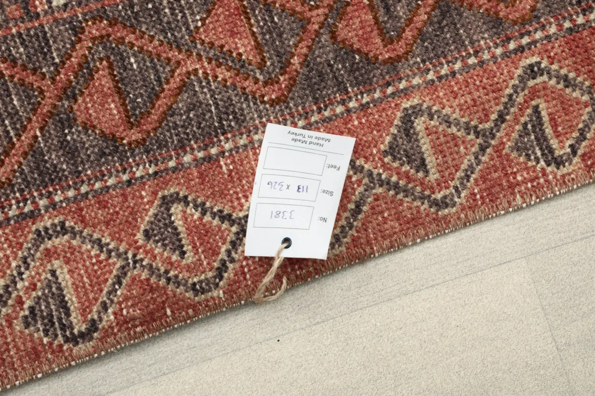Corner of the rug with an identification tag, showing the texture of the border.
