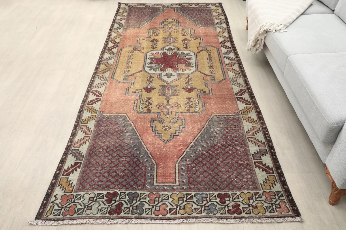 Vintage Anatolian rug on a light floor next to a gray sofa in a room setting