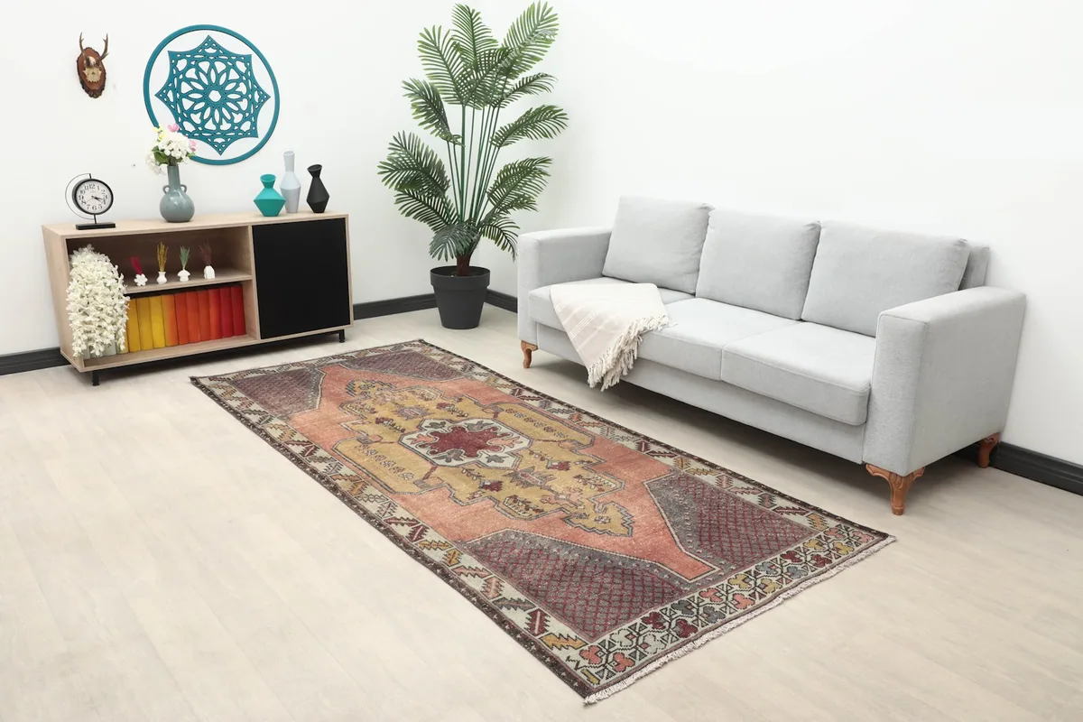 Full room view of the rose and gold rug with a sofa, plant, and decor