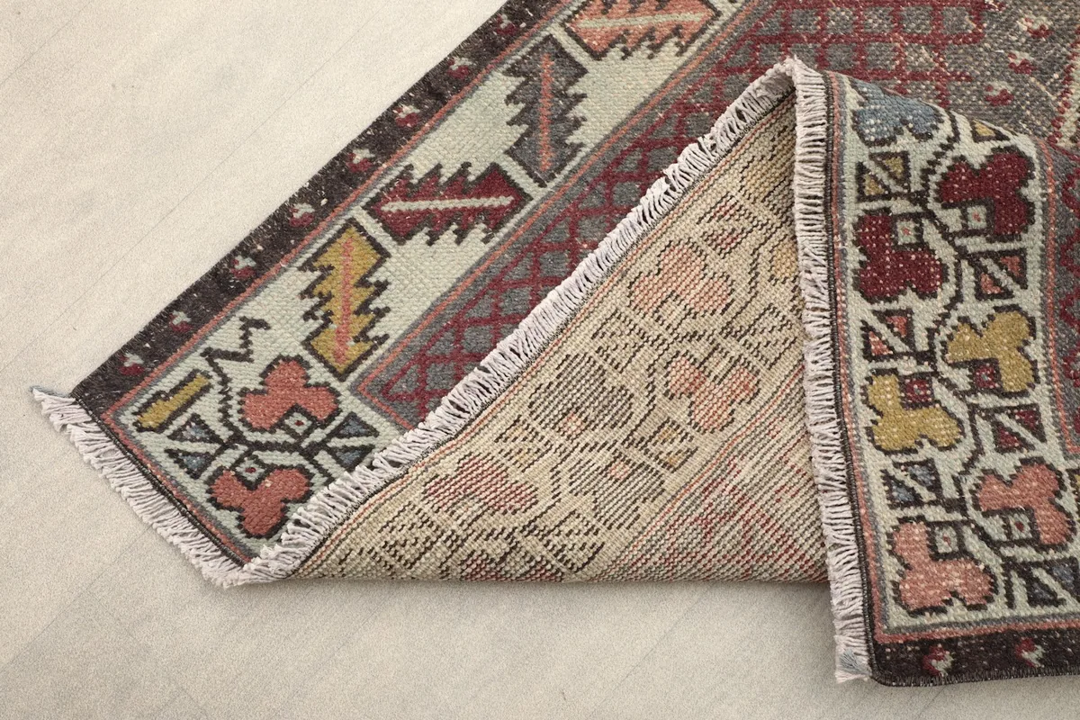 Corner of the rug folded to show the back, fringes, and border design