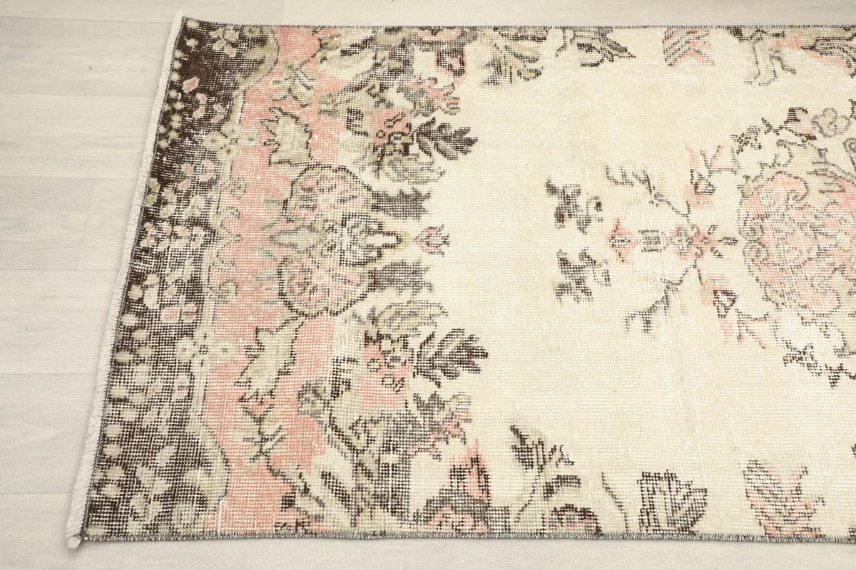 Detailed view of the rug's corner, highlighting the floral motifs and aged appearance