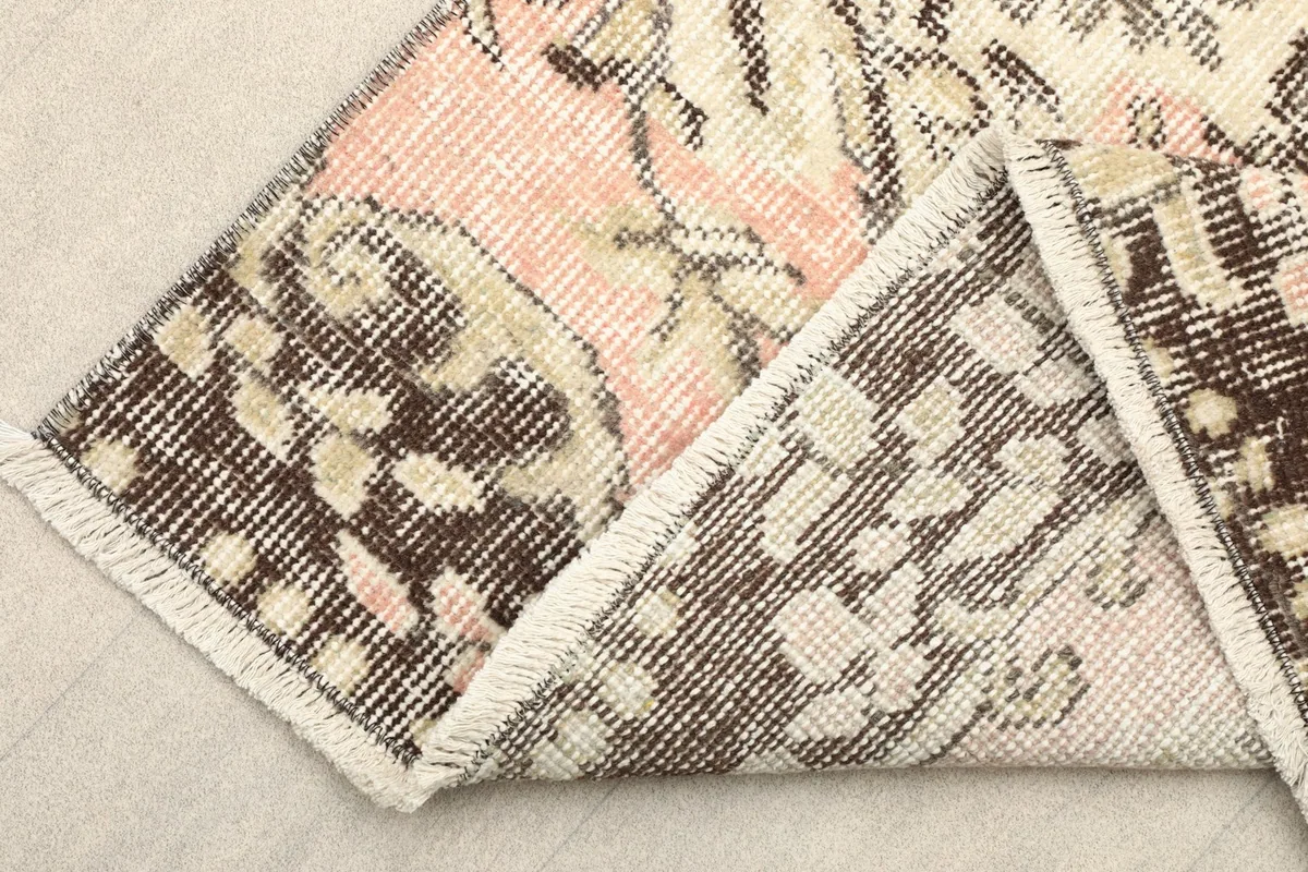 Folded corner of the rug revealing the cotton foundation and reverse side of the knots