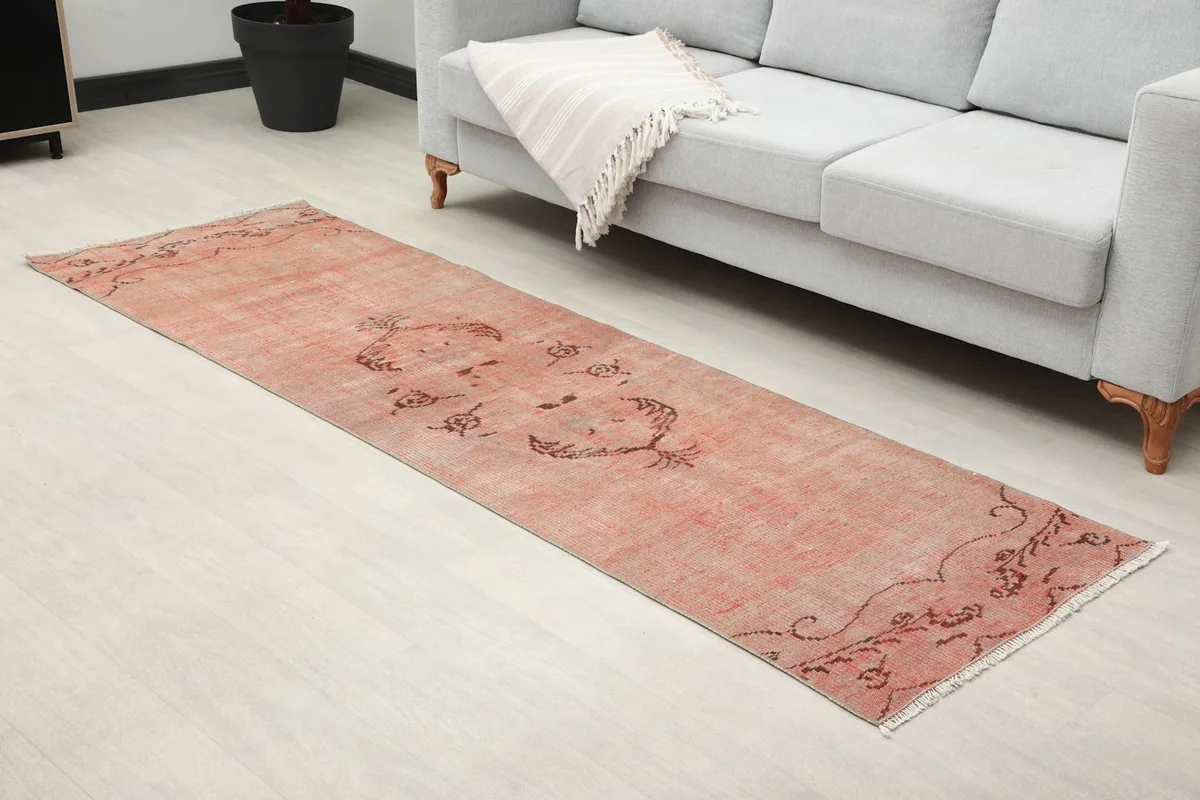 Closer room view of the rose runner rug, highlighting its placement next to a sofa.