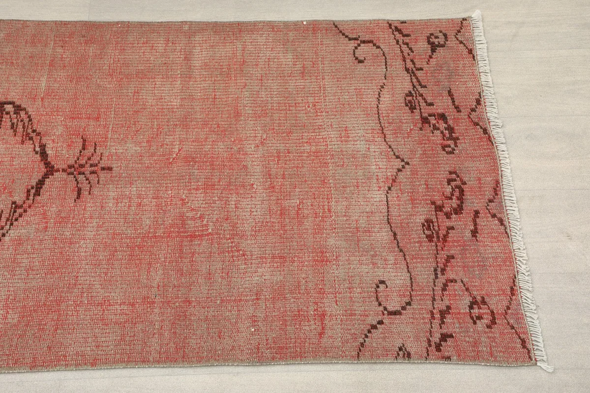 Close-up of the end border and field of the rose runner rug, showing faded colors and tribal patterns.