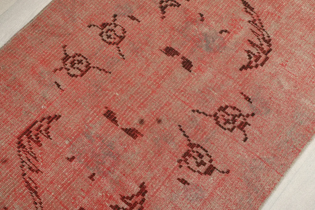 Mid-section detail of the rose runner rug, focusing on the central tribal motifs and subtle wear.