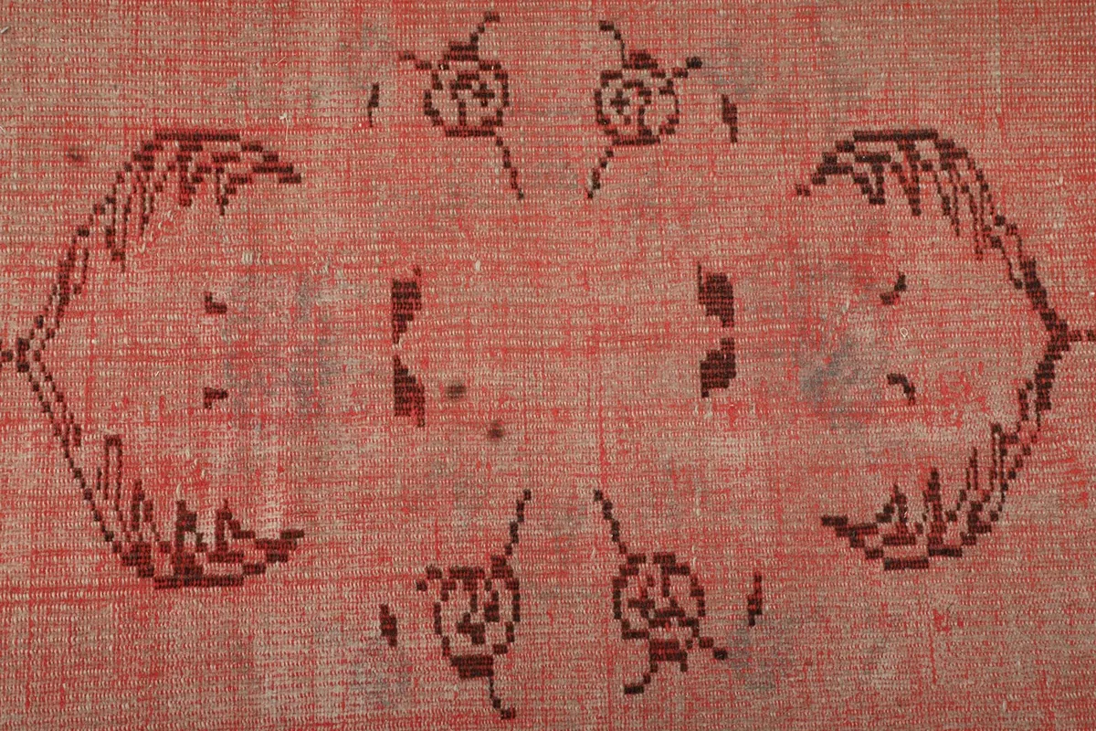 Overhead close-up of the central tribal motif on the rose runner rug, showing knot details.