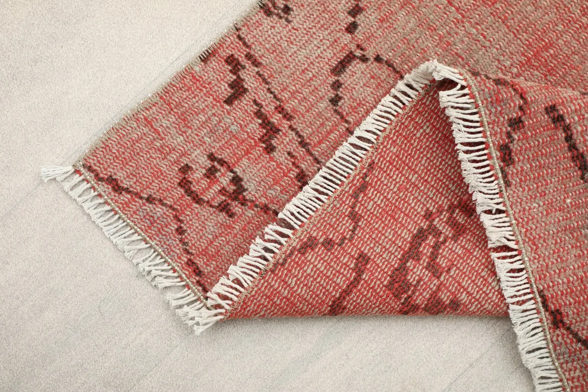 Folded corner of the rose runner rug, revealing the wool pile and cotton foundation.