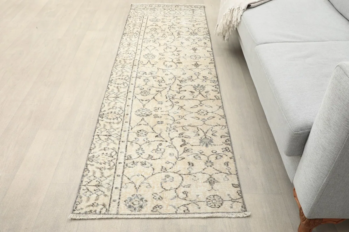 Vintage Anatolian runner rug in a living room setting next to a gray sofa, showing its length