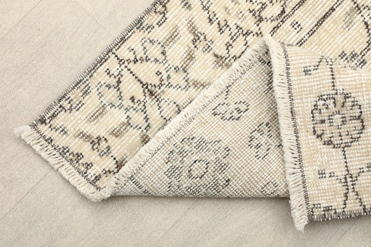 View of the rug's reverse side and folded corner, showing the cotton foundation and knotting
