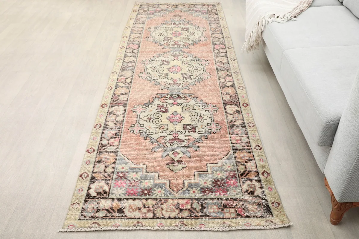 Rust runner rug in a room setting, showing its length and colors next to a light gray sofa.