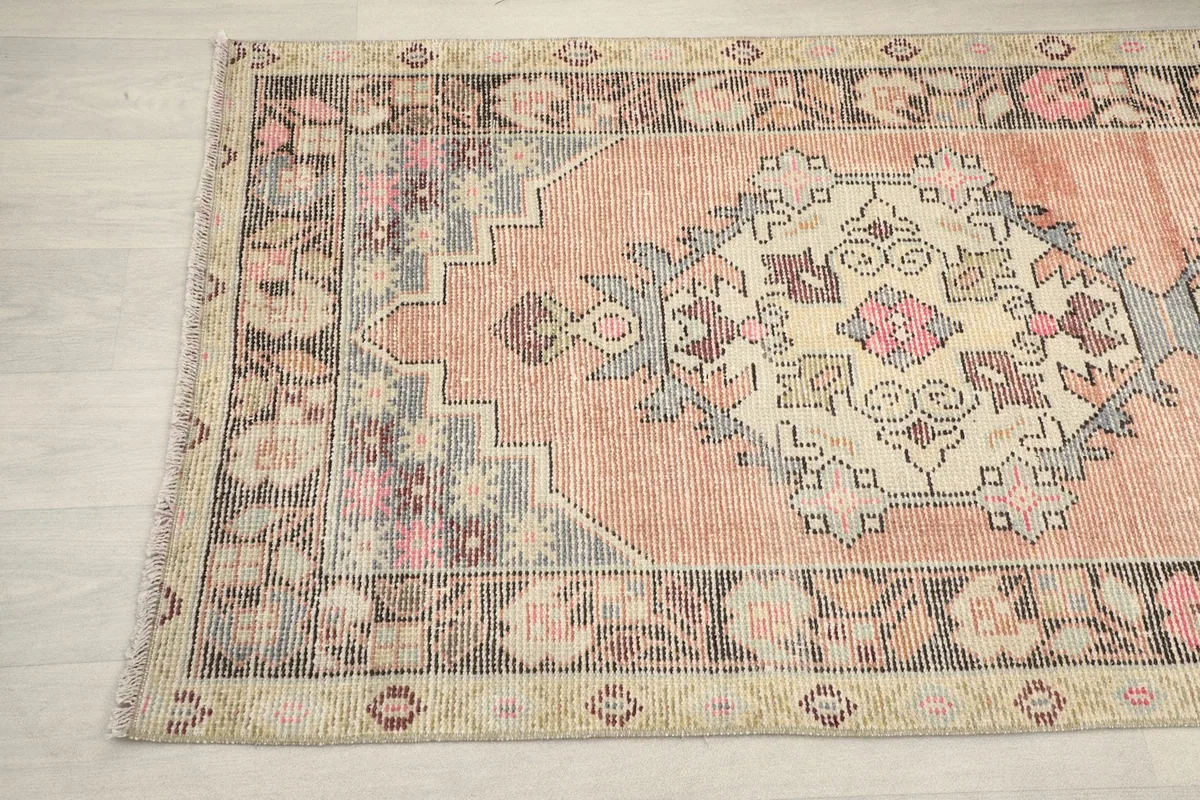 Detail showing the other end of the rust runner rug, including its border and motifs.