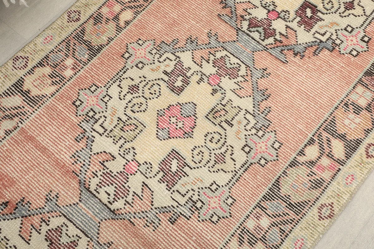 Close-up of a central geometric medallion on the rust runner rug, showing color variations and wear.