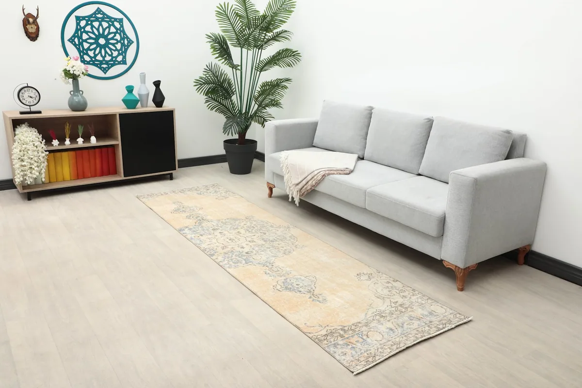 Beige and blue vintage runner rug in a living room setting with a gray sofa and light wood floor.