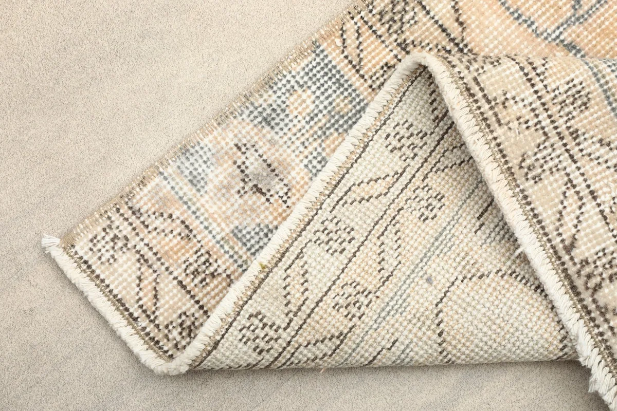 Folded corner revealing the back of the hand-knotted rug and its cotton foundation.
