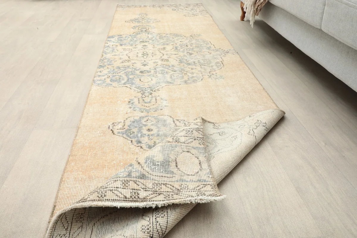 Partial view of the rug rolled back, highlighting the textile's character and construction.