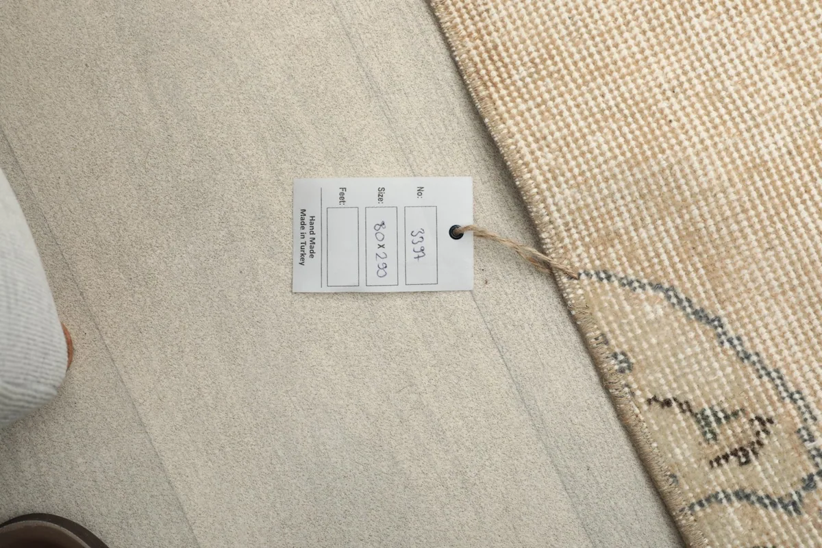 Close-up of the rug's product tag displaying its size and origin, lying on the floor.