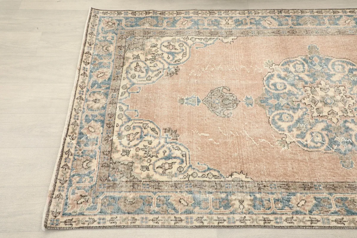 Angled view highlighting the patina and colors of the rose and blue vintage rug